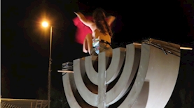 המפגינה המתפשטת מעל סמל המנורה, צילום: אם תרצו